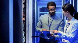 An image of a male and female data center technicians discussing how to optimize dat center prerformance.